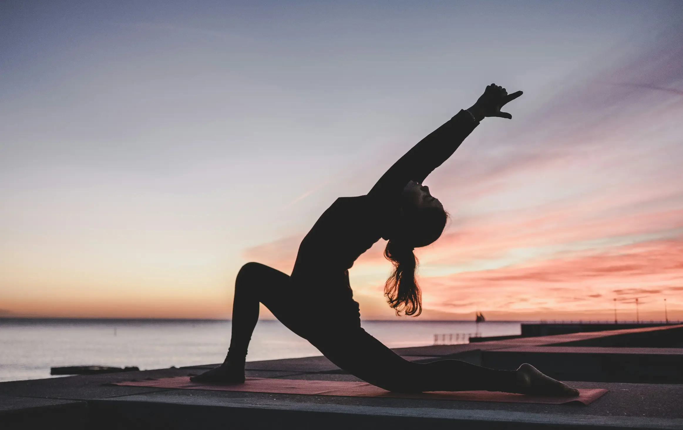 woman in a stretching yoga position near a lake